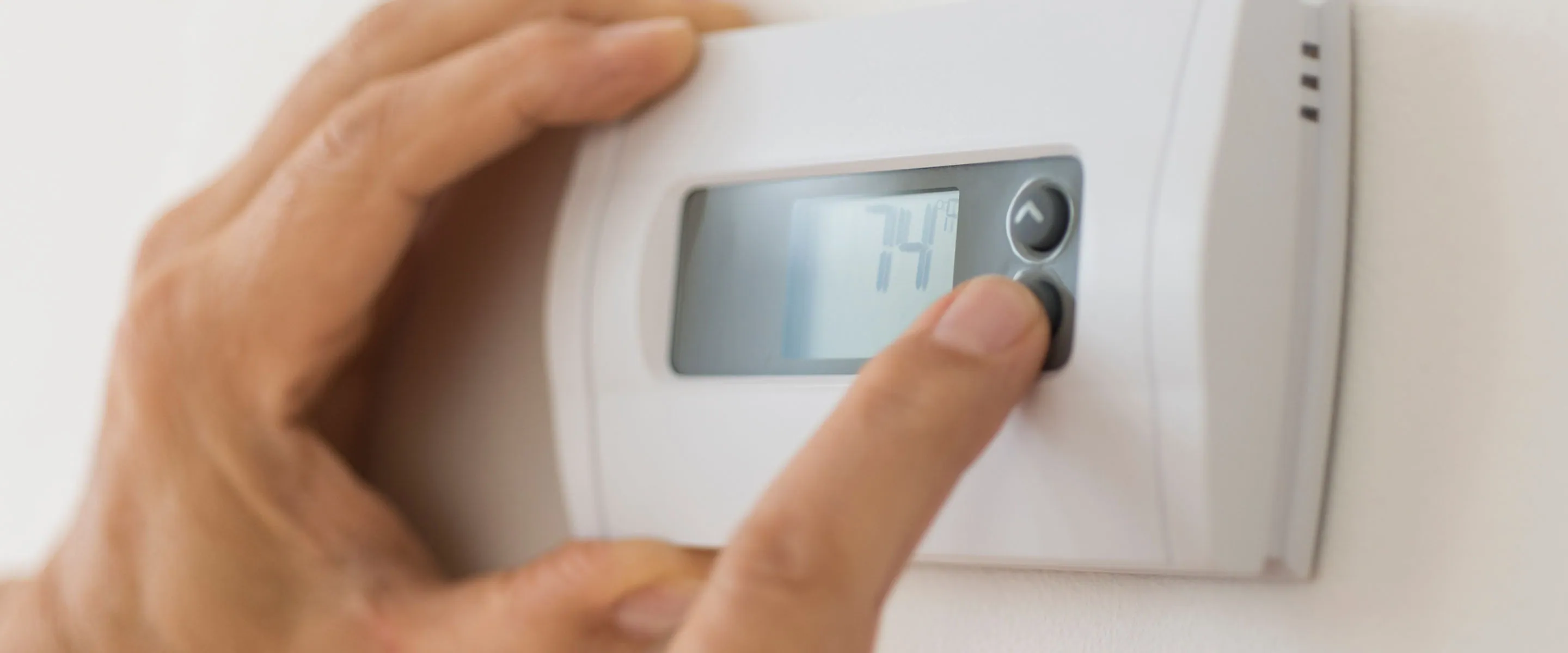 Hand adjusting a wall thermostat